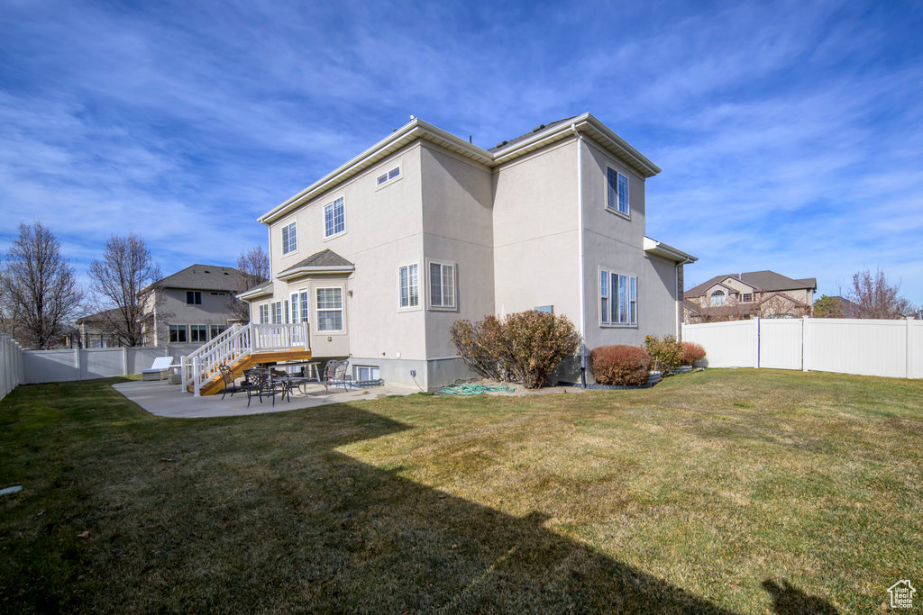 Back of property with a patio area, a yard, and a deck