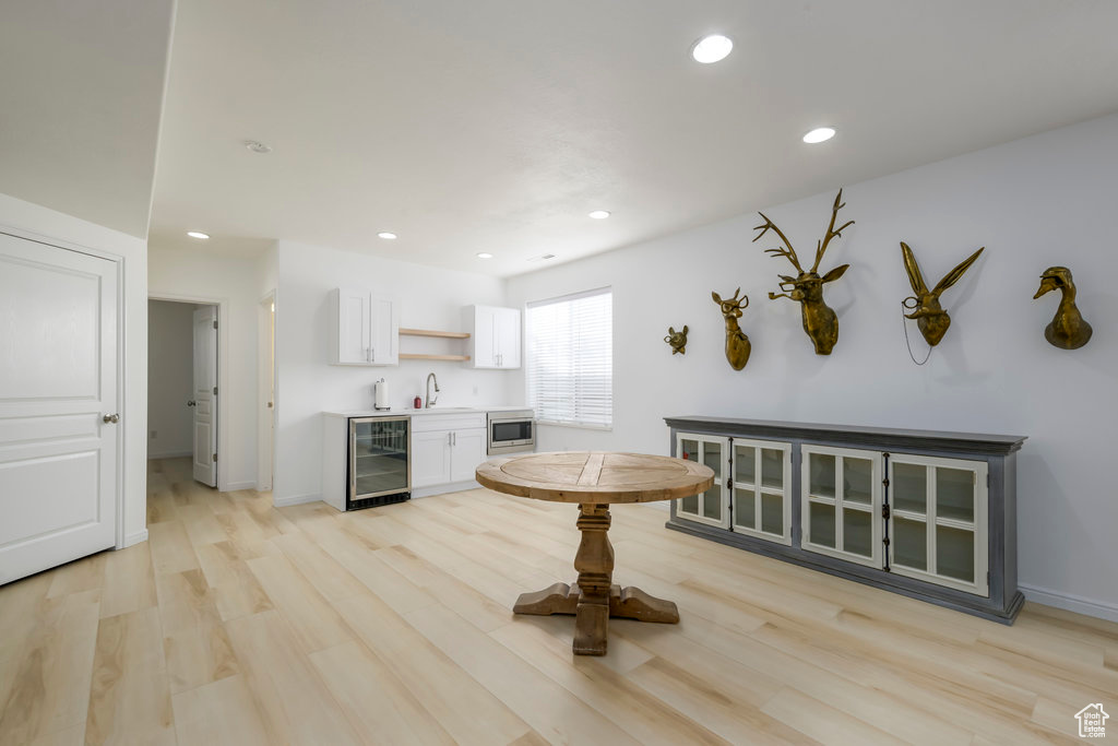 Kitchen featuring white cabinets, light wood-type flooring, beverage cooler, and sink