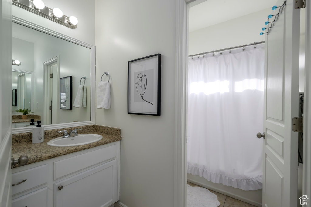 Bathroom with tile patterned floors, shower / tub combo with curtain, and vanity
