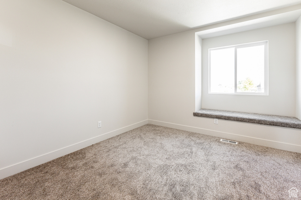 Carpeted empty room featuring baseboards and visible vents