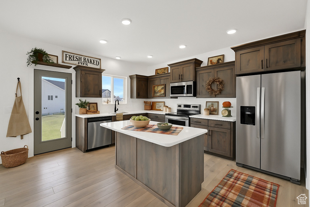 Kitchen featuring stainless steel appliances, dark brown cabinets, a sink, light countertops, and recessed lighting