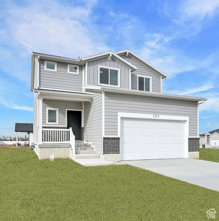 View of front facade featuring covered porch, board and batten siding, driveway, and a front lawn