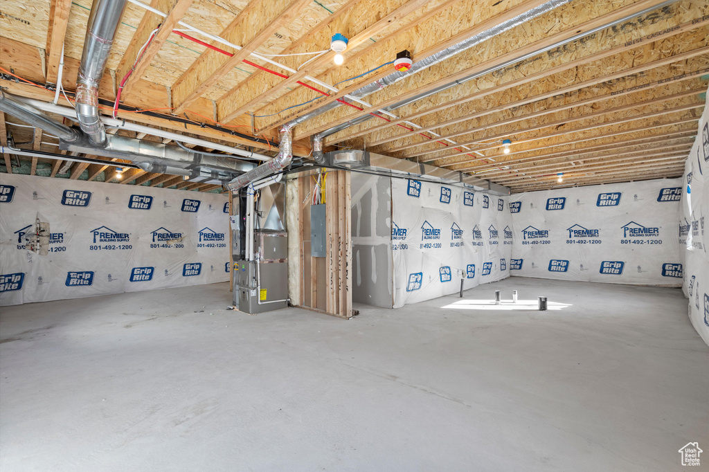 Unfinished basement featuring electric panel and heating unit