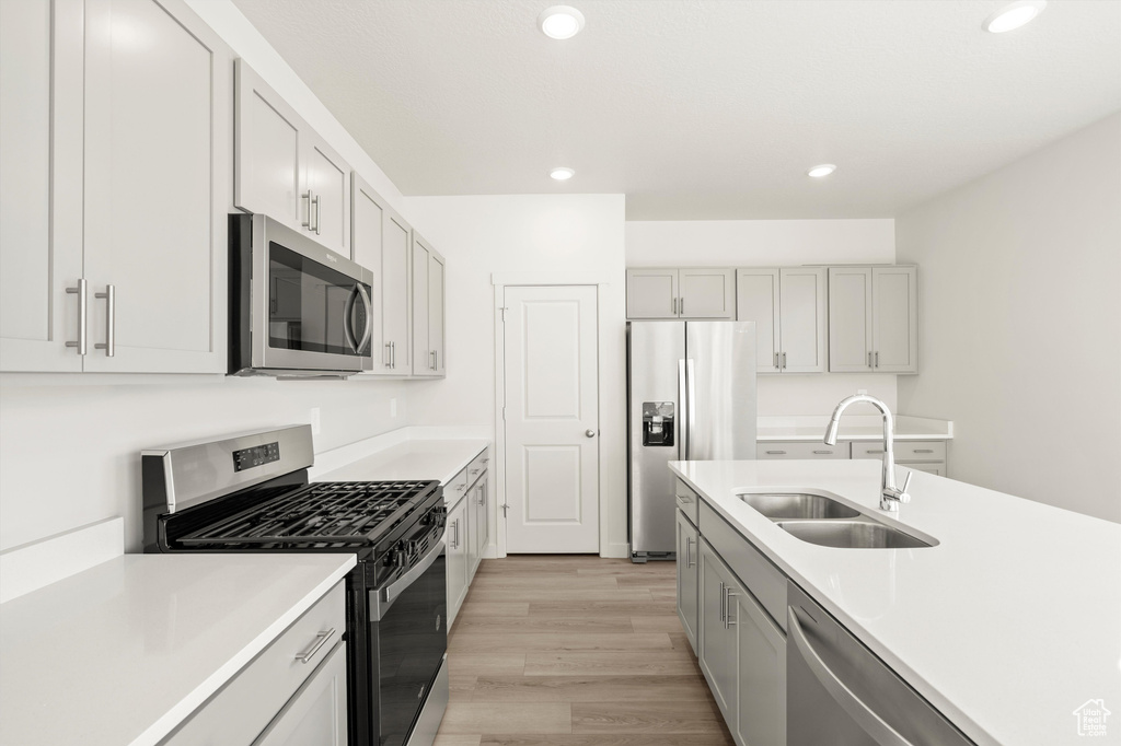 Kitchen with appliances with stainless steel finishes, recessed lighting, light wood-type flooring, and light countertops