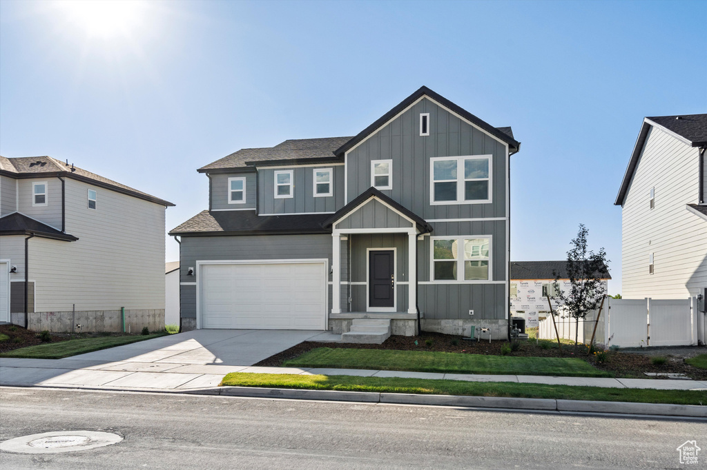 View of front of property with board and batten siding, concrete driveway, and an attached garage