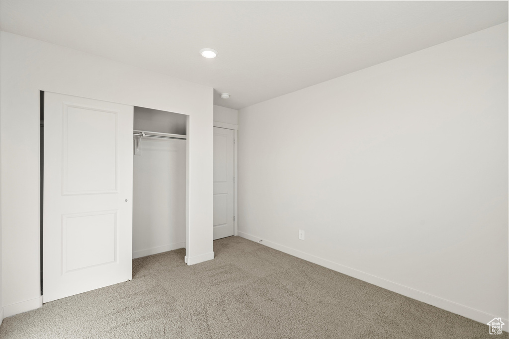 Unfurnished bedroom with light colored carpet, a closet, and recessed lighting