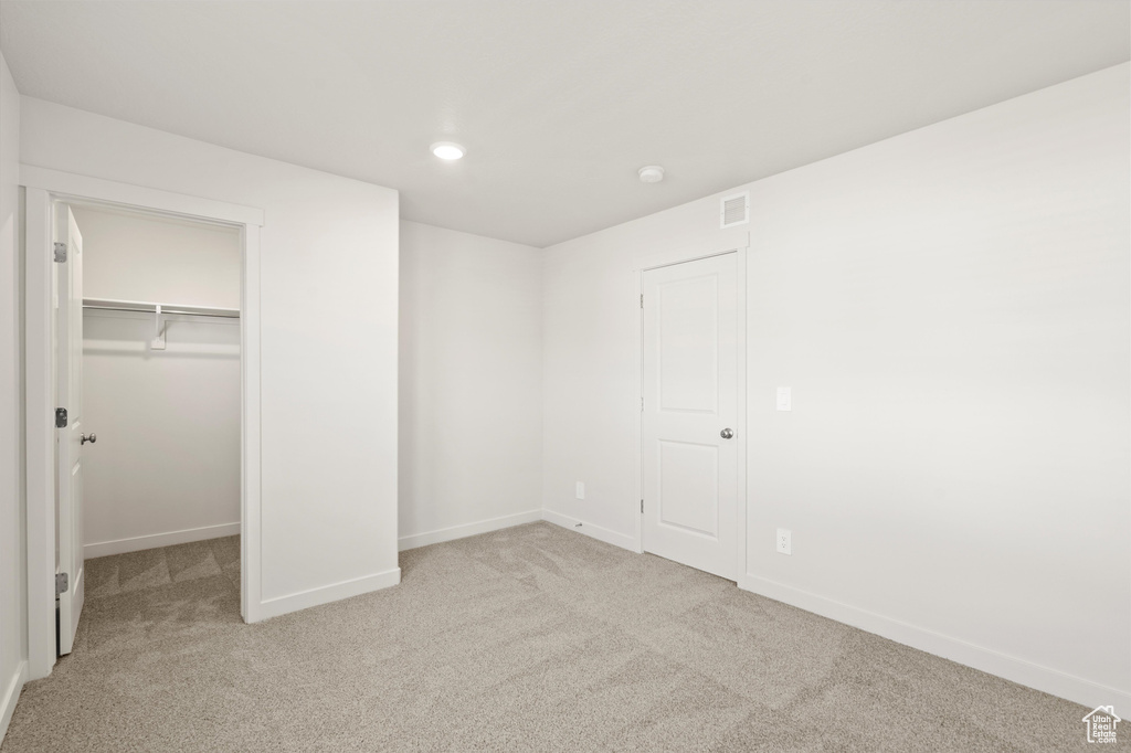 Unfurnished bedroom with carpet, a spacious closet, recessed lighting, and a closet
