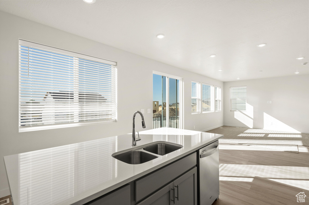 Kitchen with dishwasher, open floor plan, wood finished floors, light countertops, and recessed lighting