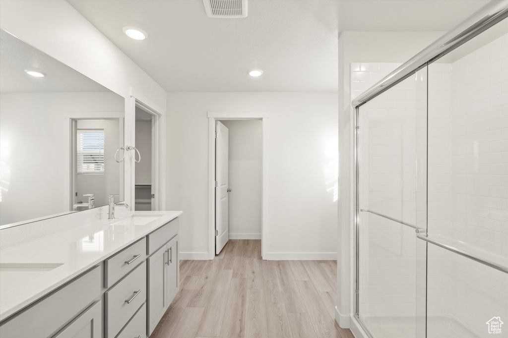 Full bath featuring a stall shower, wood finished floors, double vanity, and recessed lighting