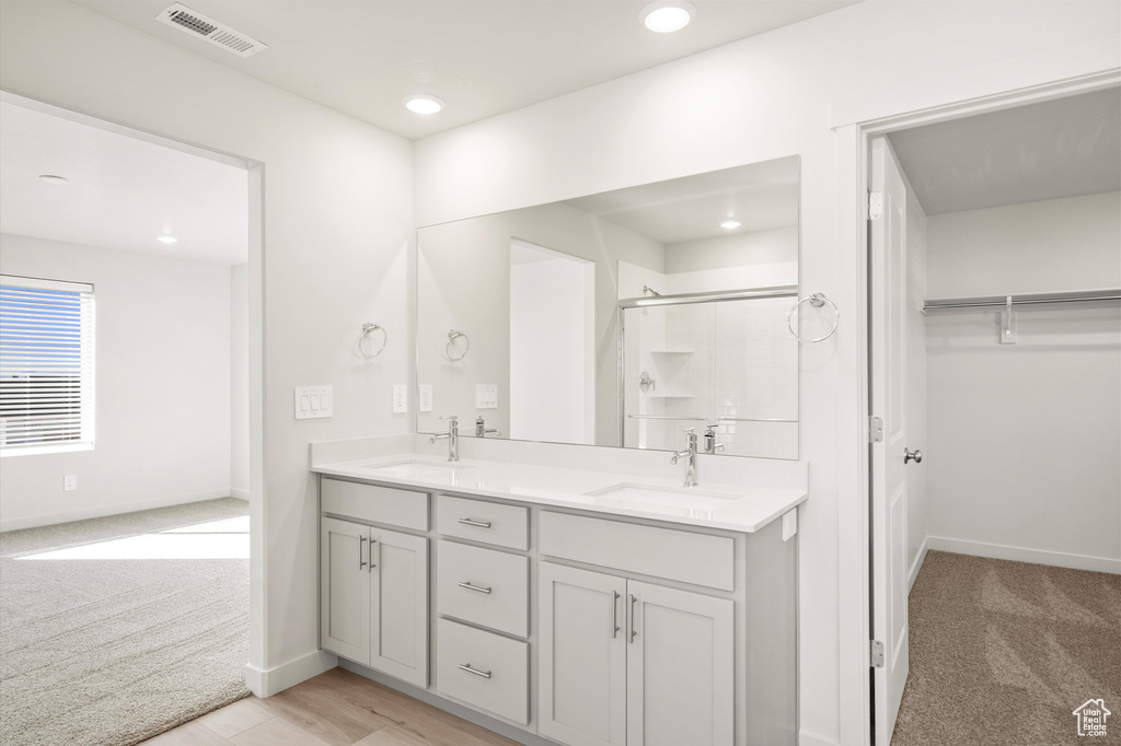 Bathroom with a stall shower, double vanity, a walk in closet, and recessed lighting