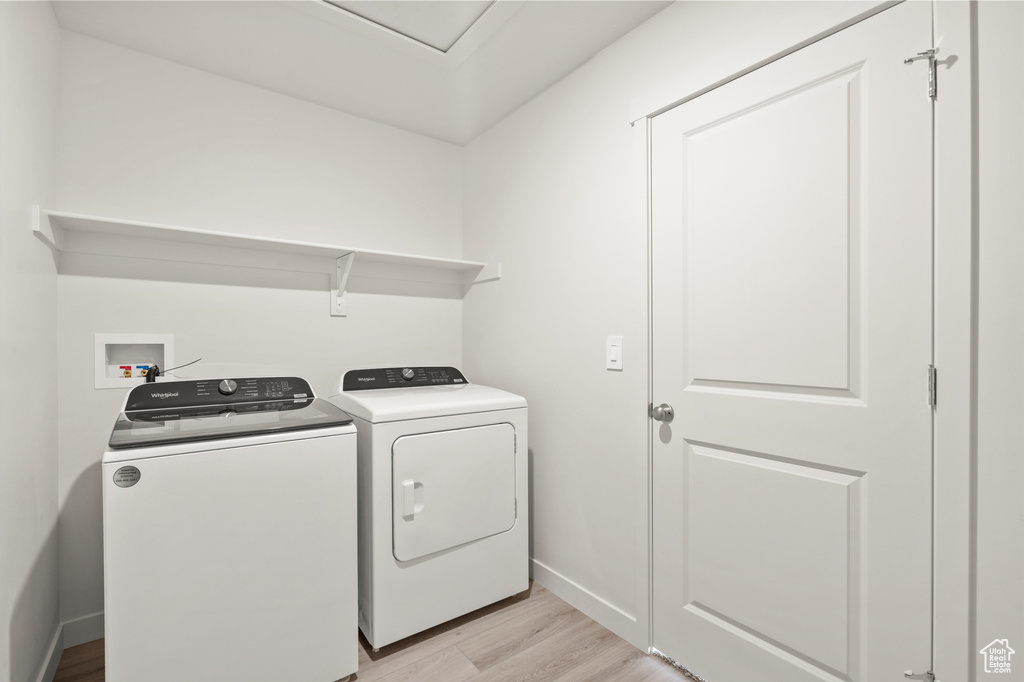 Laundry area featuring light wood-style floors and separate washer and dryer