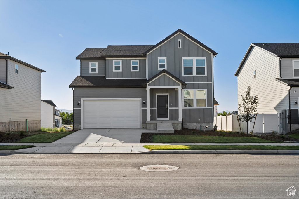 View of front facade with board and batten siding, driveway, and an attached garage