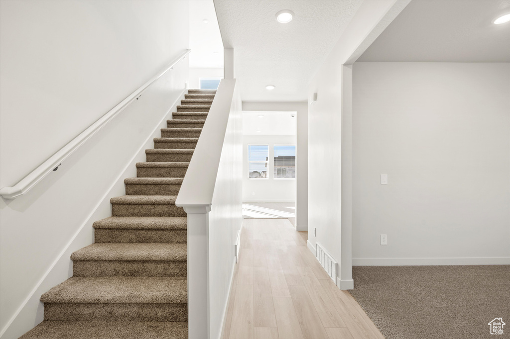 Stairway featuring wood finished floors and recessed lighting