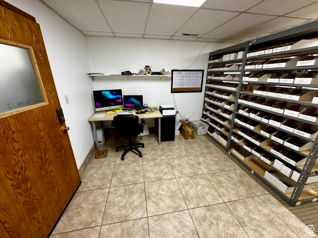 Office area with light tile patterned floors, built in desk, and a drop ceiling