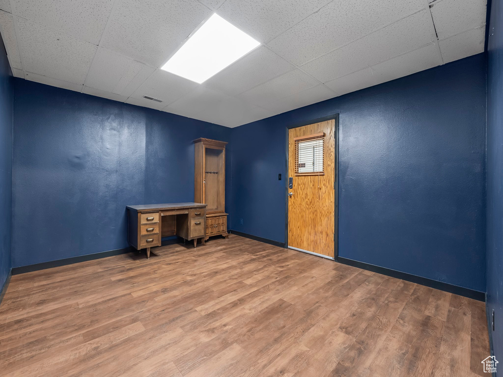 Unfurnished office featuring a paneled ceiling and hardwood / wood-style floors