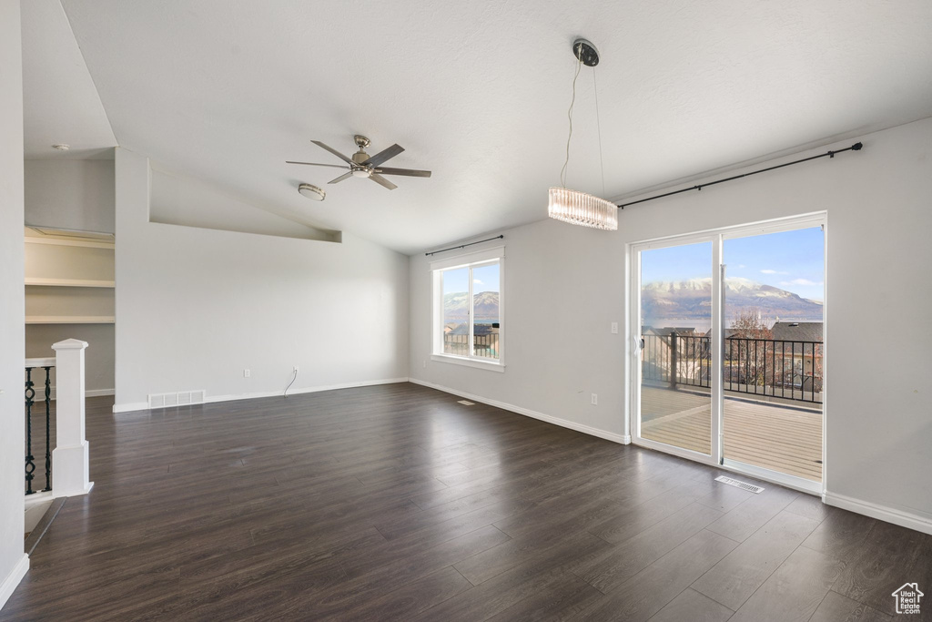 Unfurnished living room with lofted ceiling, a mountain view, dark wood-type flooring, and ceiling fan with notable chandelier