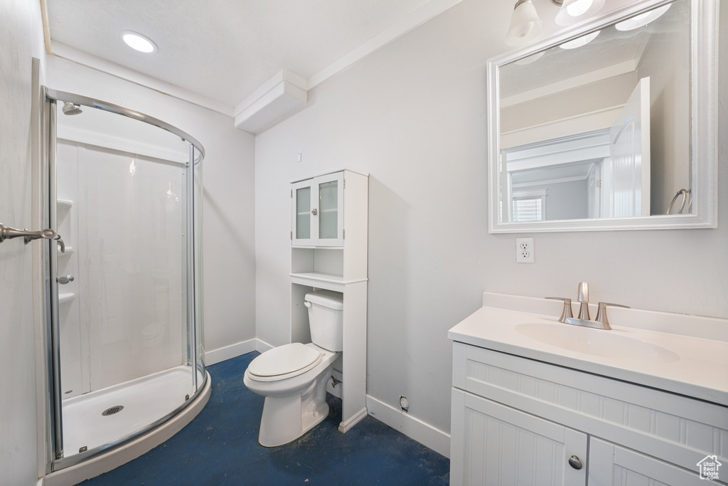 Bathroom with crown molding, vanity, a shower with shower door, and toilet