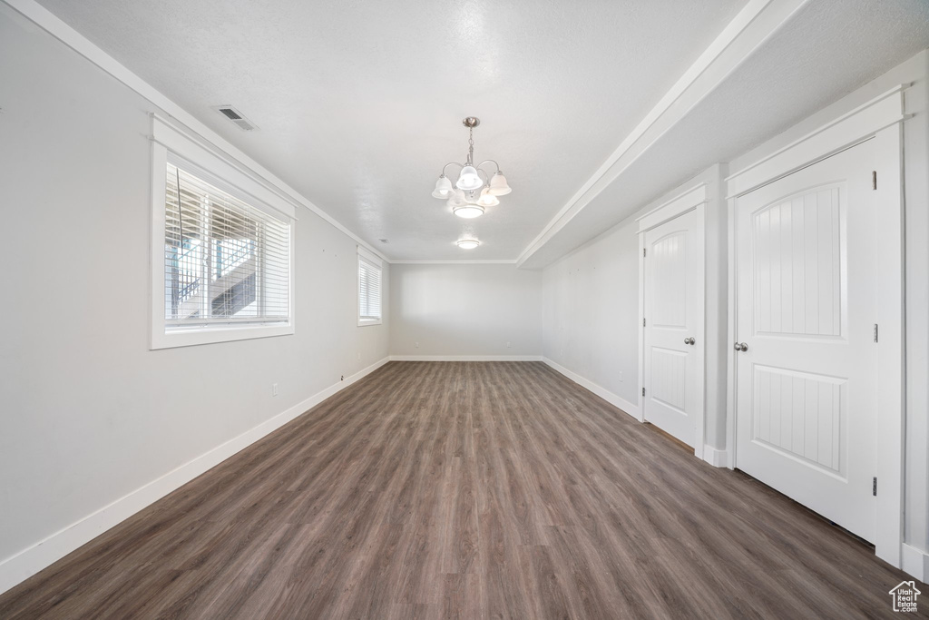 Spare room featuring dark hardwood / wood-style floors, ornamental molding, and an inviting chandelier