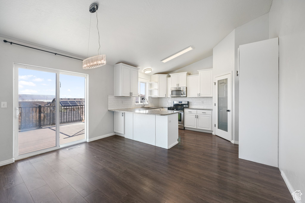 Kitchen with lofted ceiling, sink, kitchen peninsula, appliances with stainless steel finishes, and white cabinetry