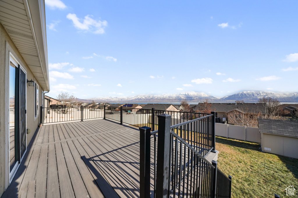 Wooden terrace featuring a lawn, a mountain view, and a storage unit