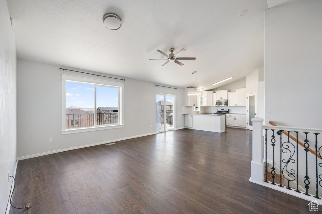 Unfurnished living room featuring dark hardwood / wood-style floors, ceiling fan, and lofted ceiling