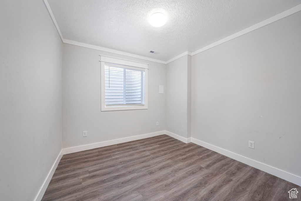 Unfurnished room featuring a textured ceiling, dark hardwood / wood-style floors, and ornamental molding