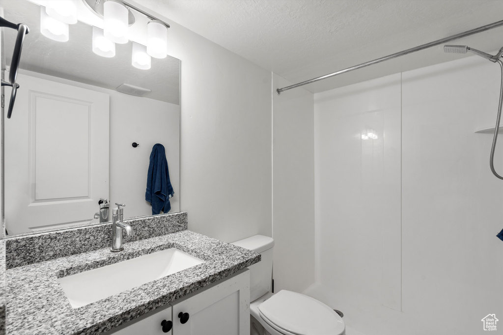 Bathroom with a shower, vanity, a textured ceiling, and toilet