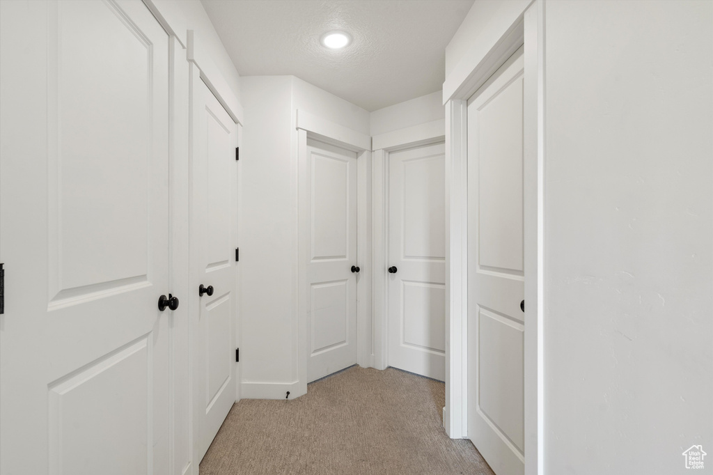 Corridor featuring light carpet and a textured ceiling