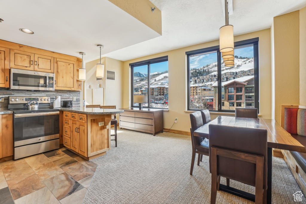 Kitchen with tasteful backsplash, kitchen peninsula, pendant lighting, a breakfast bar, and appliances with stainless steel finishes