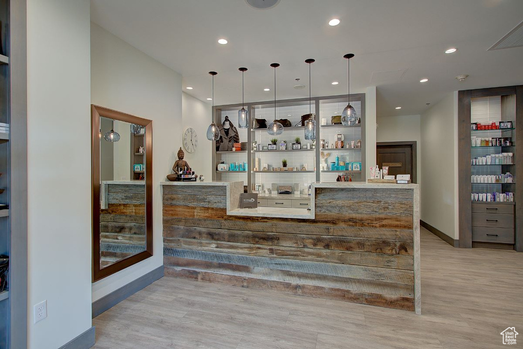 Bar featuring pendant lighting and light hardwood / wood-style flooring