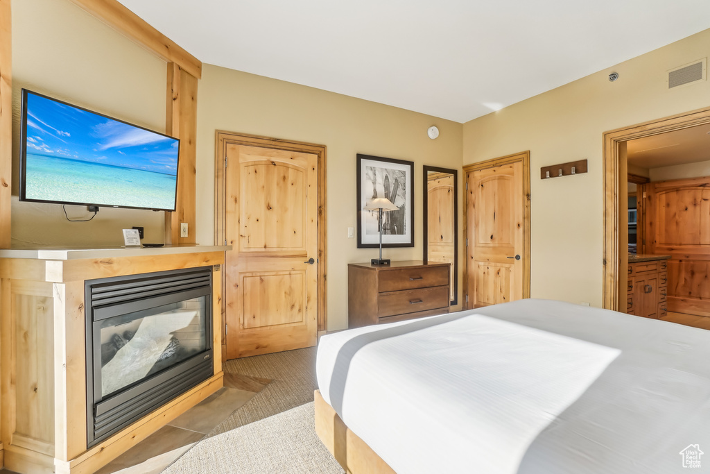 Bedroom with a multi sided fireplace and light carpet