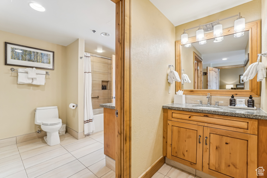 Full bathroom with tile patterned flooring, shower / bath combination with curtain, toilet, and vanity