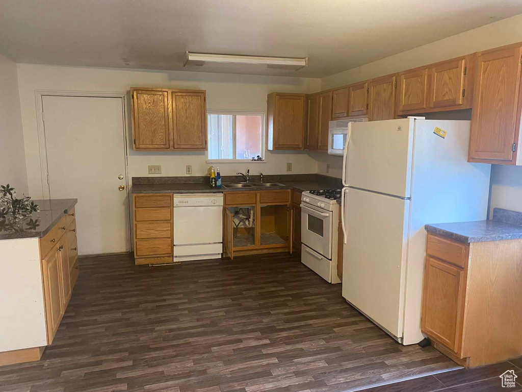 Kitchen featuring sink, dark hardwood / wood-style floors, and white appliances