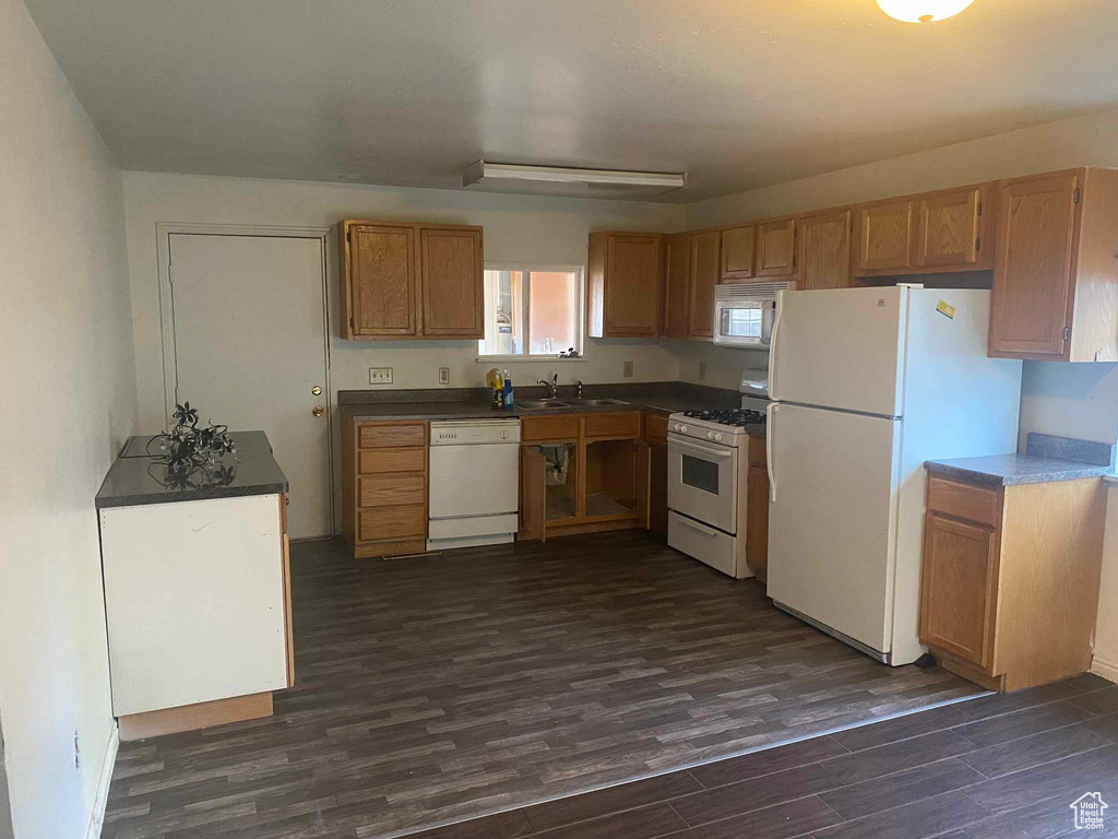 Kitchen with sink, dark hardwood / wood-style floors, and white appliances