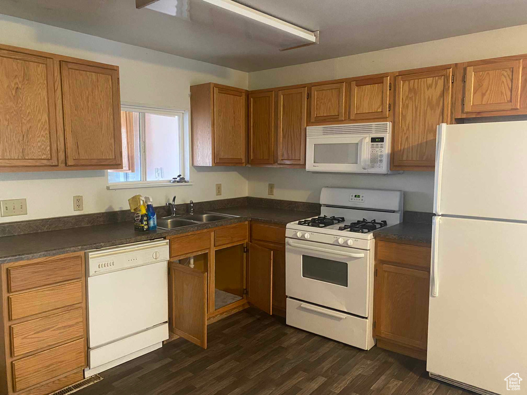 Kitchen featuring sink, dark wood-type flooring, and white appliances