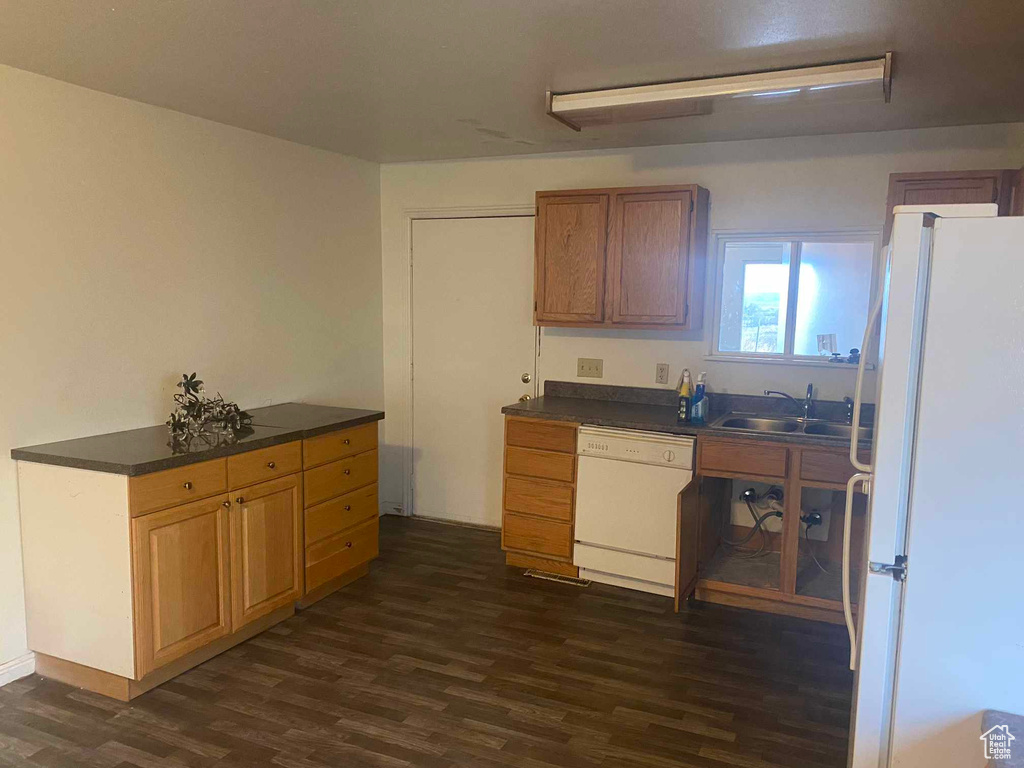 Kitchen with white appliances, dark wood-type flooring, and sink