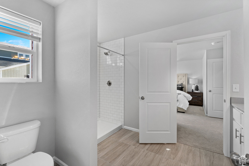 Bathroom featuring a tile shower, vanity, and toilet