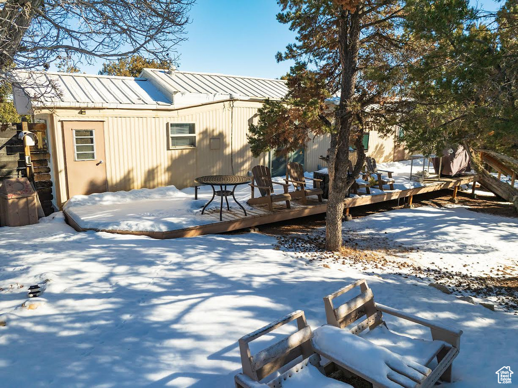 Snow covered back of property featuring a wooden deck