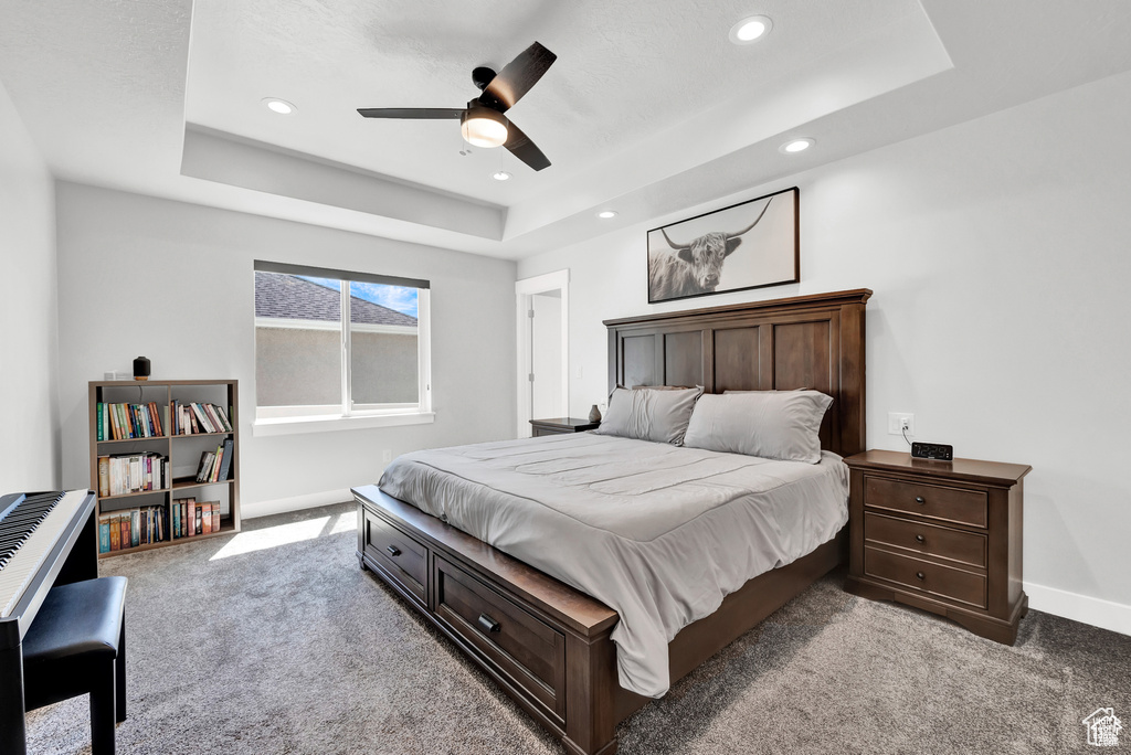 Bedroom featuring carpet flooring, a raised ceiling, and ceiling fan