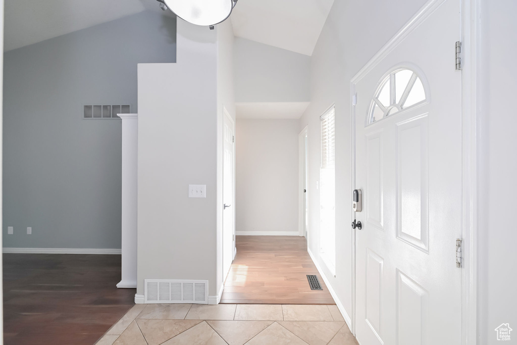 Entrance foyer with high vaulted ceiling, light wood-style floors, and baseboards