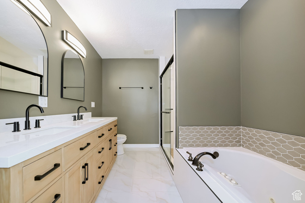 Full bathroom featuring a garden tub, marble finish floors, double vanity, a shower stall, and toilet