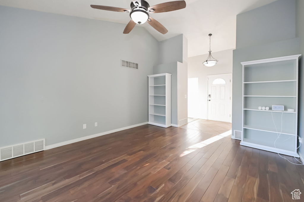 Unfurnished living room featuring high vaulted ceiling, a ceiling fan, wood finished floors, and baseboards