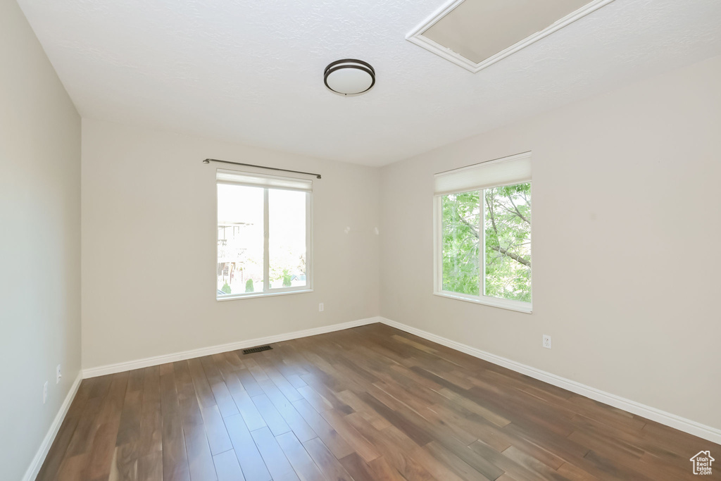 Spare room featuring plenty of natural light, baseboards, and dark wood-style floors