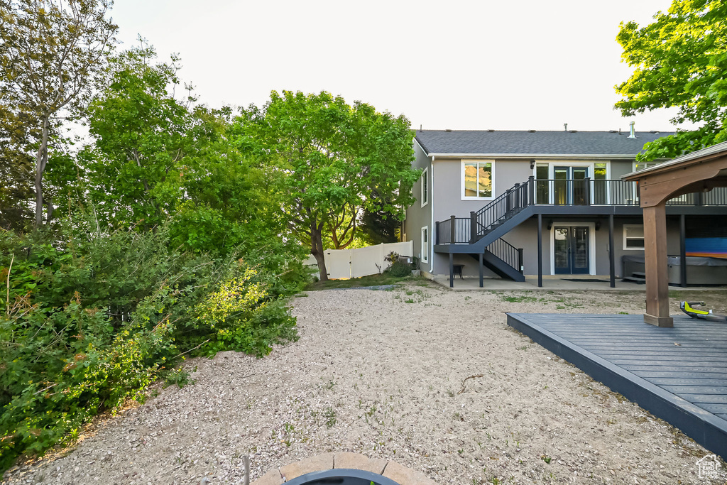 Rear view of house with stairs, a wooden deck, fence, and a patio area