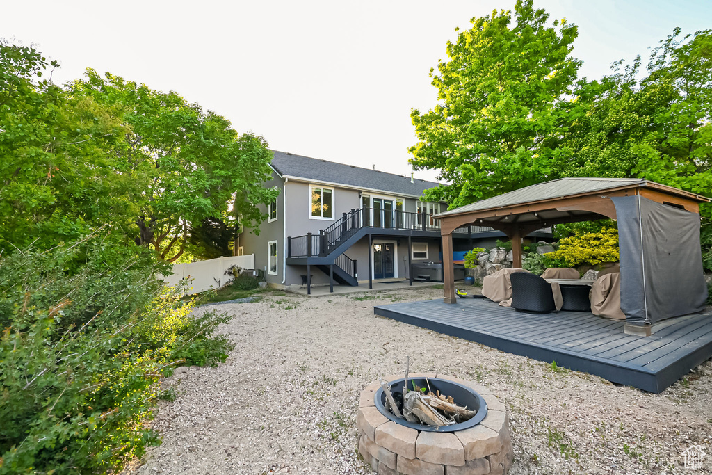 Rear view of property featuring an outdoor fire pit, a gazebo, stairway, a deck, and fence