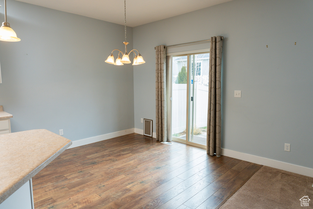 Unfurnished dining area with a chandelier and dark wood-type flooring