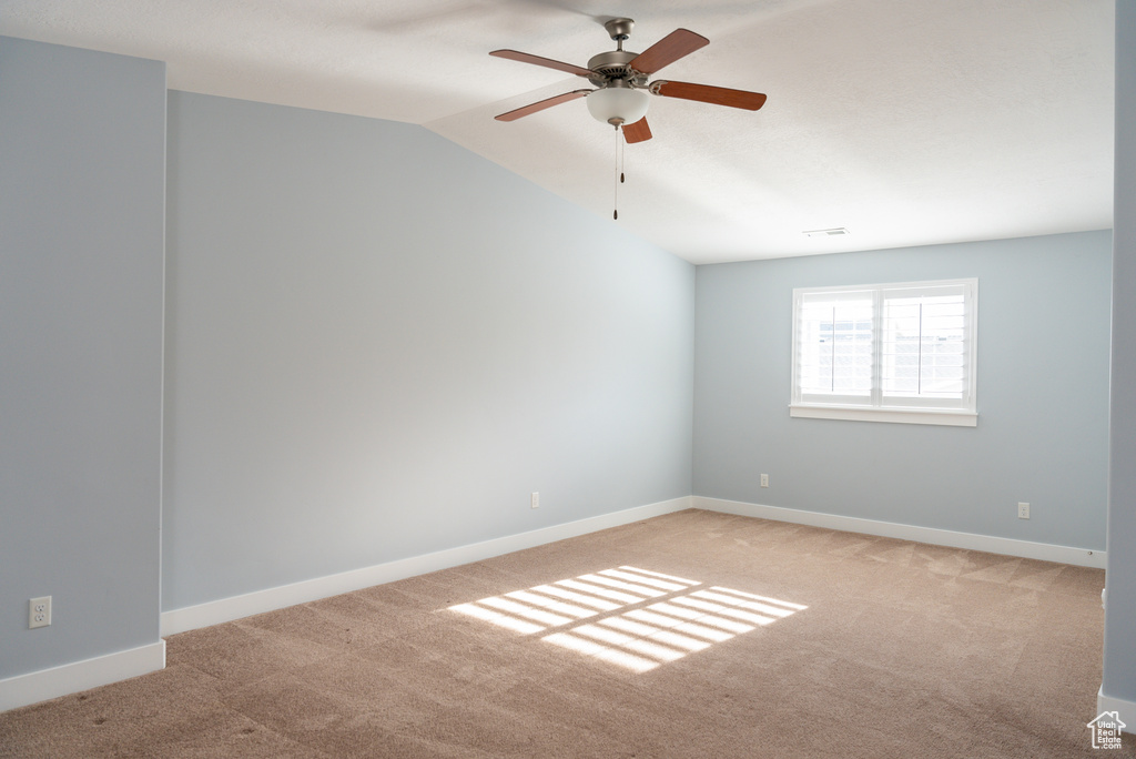 Unfurnished room with ceiling fan, light colored carpet, and vaulted ceiling