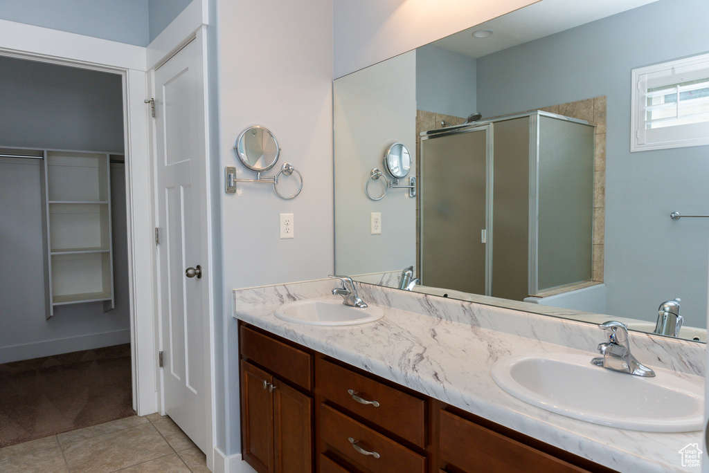 Bathroom featuring tile patterned flooring, vanity, and a shower with door