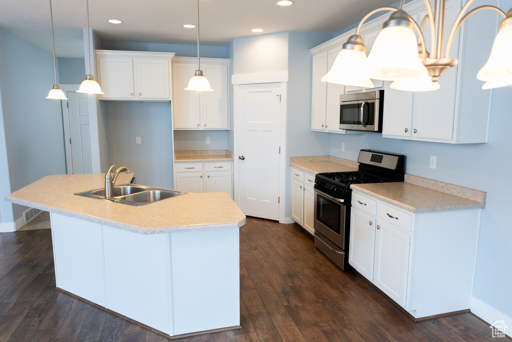 Kitchen with sink, white cabinets, stainless steel appliances, and decorative light fixtures