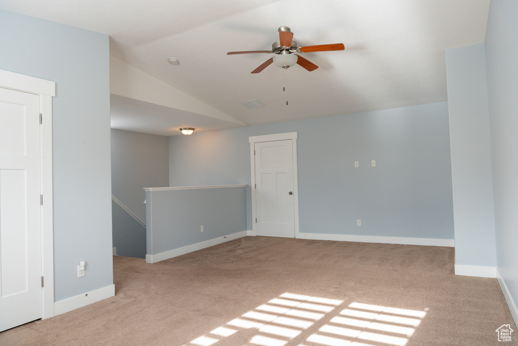 Carpeted spare room with ceiling fan and vaulted ceiling